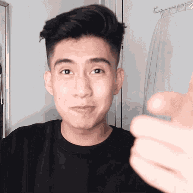 a young man in a black shirt is making a funny face in front of a mirror