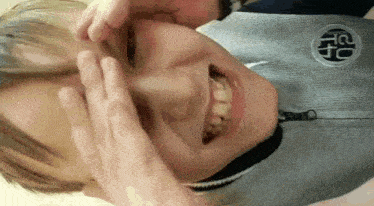 a close up of a person making a funny face with their hands on their face .