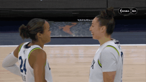 two female basketball players are looking at each other on the court