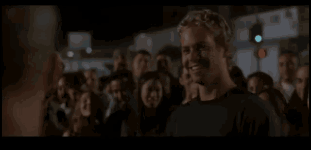 a man in a black shirt smiles in front of a crowd