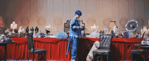 a man with blue hair is standing in front of a table with a skateboard on it