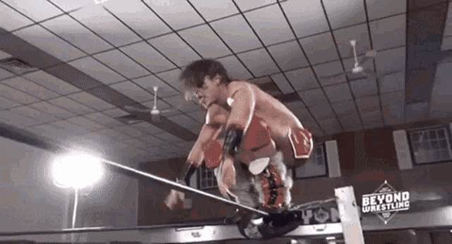 a man is jumping over a rope in a wrestling ring with beyond wrestling written on the wall behind him