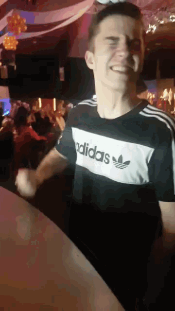 a man wearing a black and white adidas t-shirt