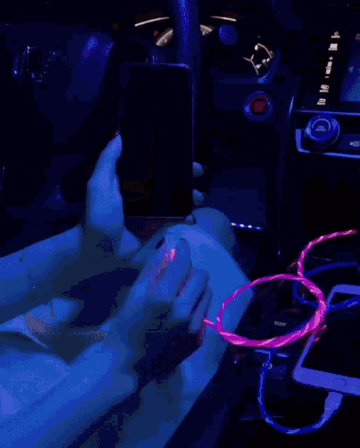 a person is holding a cell phone in their hand while it is plugged into a charger