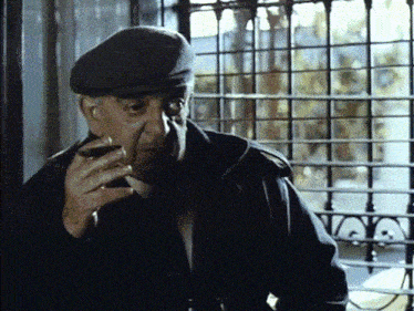a man in a hat holds a glass in his hand