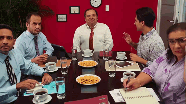 a group of people sitting around a table with plates of food and a clock that says ' aa ' on it