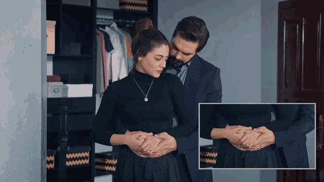 a man in a suit holds a woman 's stomach in front of a closet