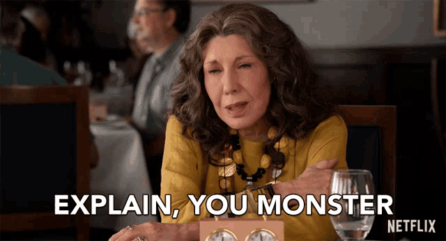 a woman sits at a table with a glass of wine and says explain you monster netflix