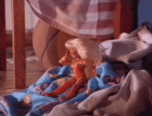 a barbie doll is laying on a pile of clothes
