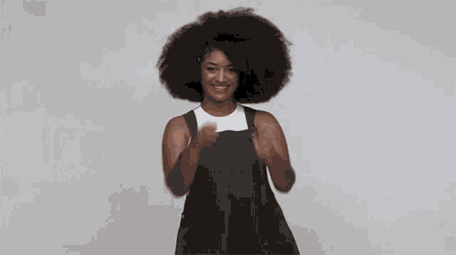 a woman wearing green overalls and a white tank top is dancing