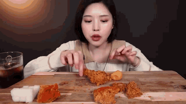 a woman sitting at a table eating fried chicken