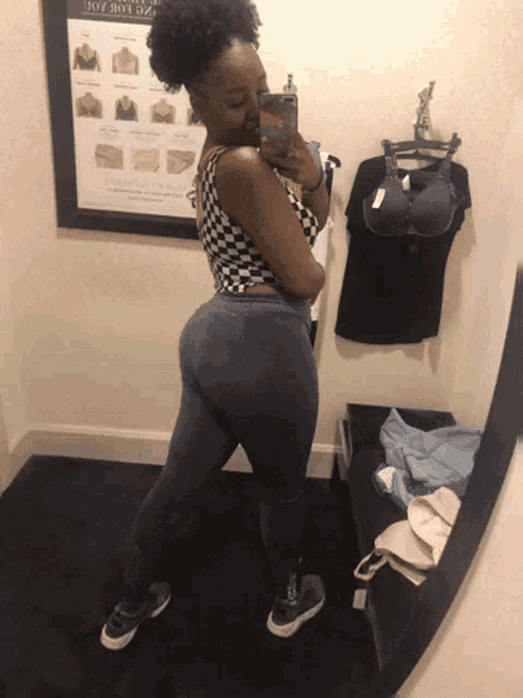 a woman taking a picture of herself in a dressing room with a sign that says joy