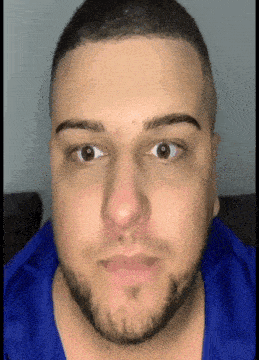 a close up of a man 's face with a beard and a blue shirt .