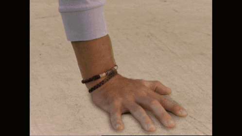 a person wearing a bracelet on their wrist has their hand on the floor