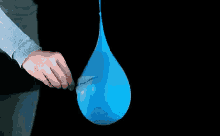 a person blowing up a blue balloon with a black background