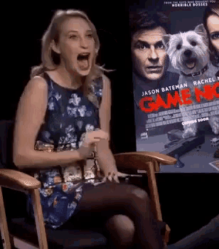 a woman is sitting in front of a poster for game night