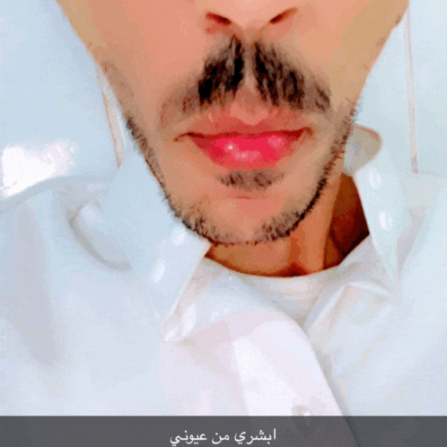 a close up of a man 's face with arabic writing on the bottom right