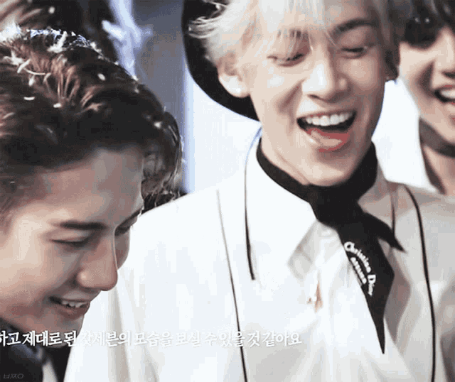 a man wearing a white shirt and a black tie laughs with another man