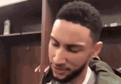 a basketball player is standing in a locker room with his eyes closed .