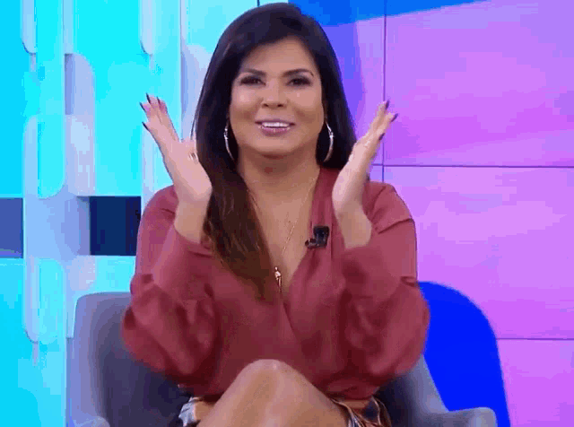 a woman is sitting in a chair with her hands in the air and smiling .