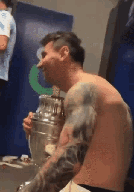 a shirtless man is holding a trophy in his hands .