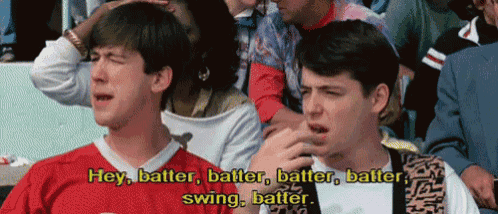 two men are sitting in a crowd and one of them is saying hey batter batter batter batter swing batter ..