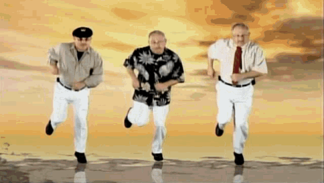 three men in suits and ties are running in a row .