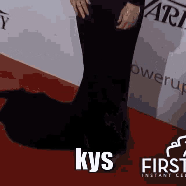 a person standing on a red carpet with the word kys written on the bottom