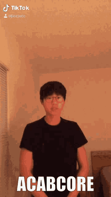 a man in a black shirt is making a funny face with the word acabcore written on it
