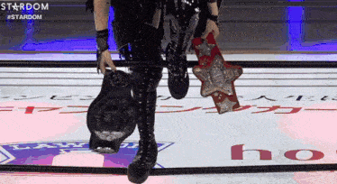 a person holding two wrestling belts in a ring that says stardom on the bottom