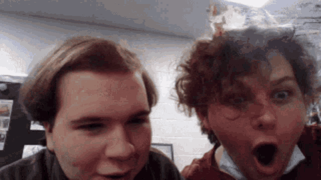 two men are posing for a picture with their mouths open and one of them is making a surprised face .