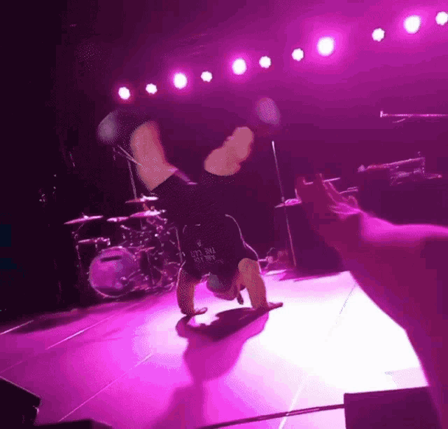 a person doing a handstand on a stage with a shirt that says " let 's roll "