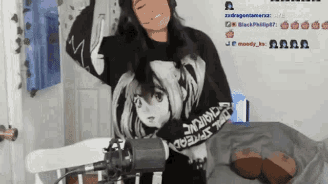 a woman is standing in front of a microphone wearing a black sweater with a picture of a girl on it
