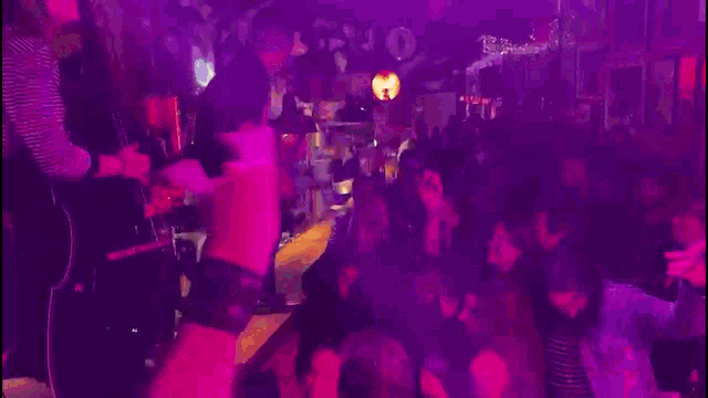 a man playing a guitar in front of a crowd in a dark room