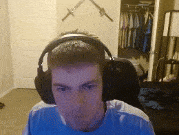 a man wearing headphones looks at the camera in a room with swords on the wall behind him