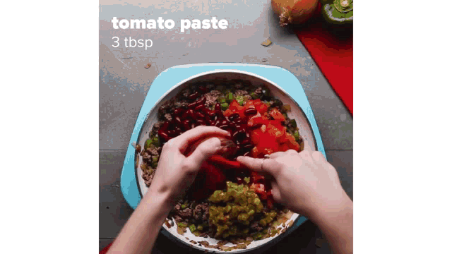 a person is adding tomato paste to a pot of food .
