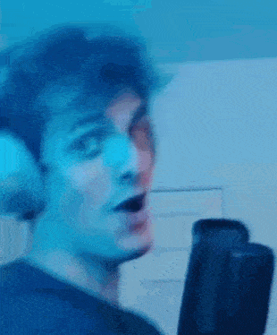 a man wearing headphones is singing into a microphone in a dark room .