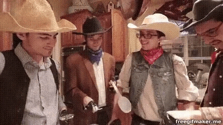 a group of people dressed up as cowboys are standing in a kitchen .