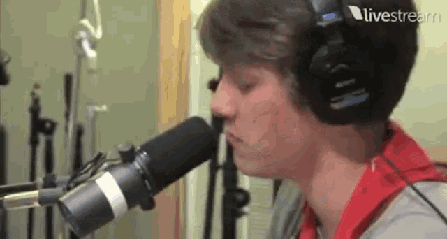 a young man wearing headphones is singing into a microphone in a recording studio .