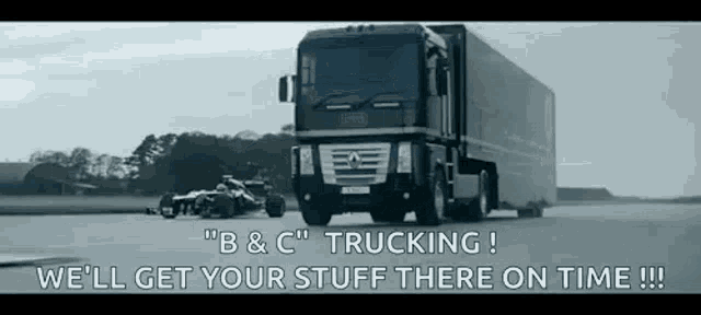 a truck is driving down a road next to a race car with the words `` we 'll get your stuff there on time ! ''