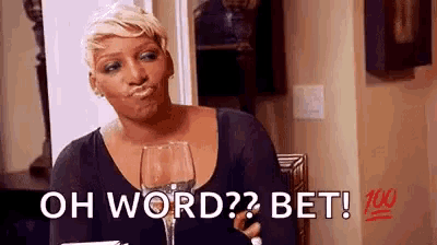 a woman is sitting at a table holding a wine glass and making a funny face .