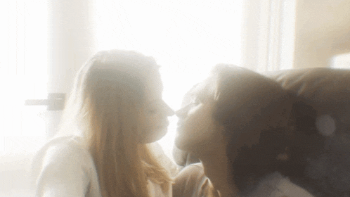 two women are kissing each other in front of a window