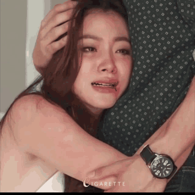 a woman is hugging a man who is wearing a watch with the word cigarette on it