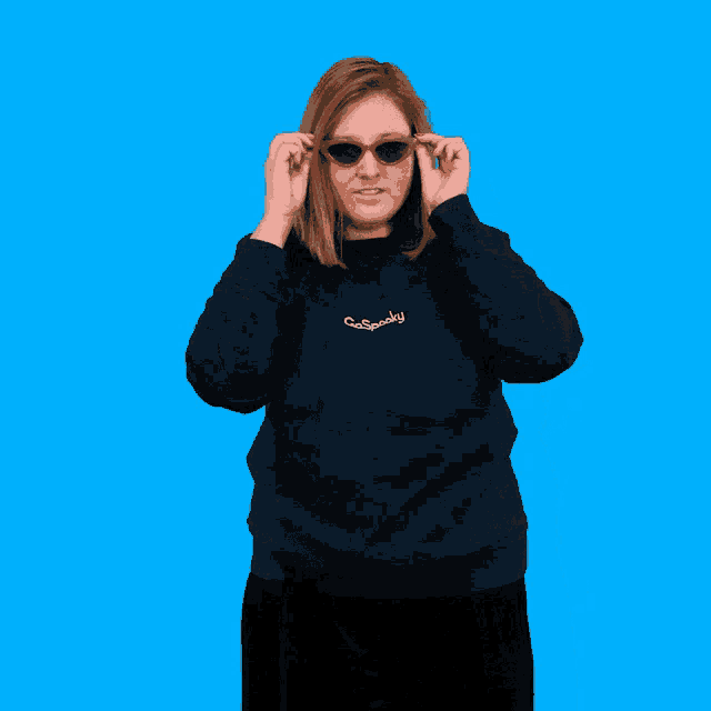 a woman wearing sunglasses and a sweatshirt that says gaspooky on it