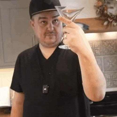 a man in a black shirt is holding a martini glass .