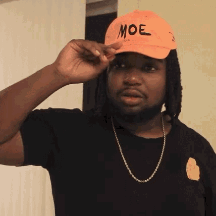 a man wearing a black shirt and an orange hat with moe written on it