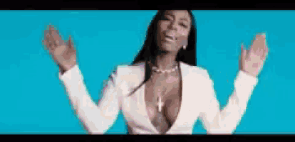 a woman with her arms outstretched is wearing a white jacket and a plunging neckline .