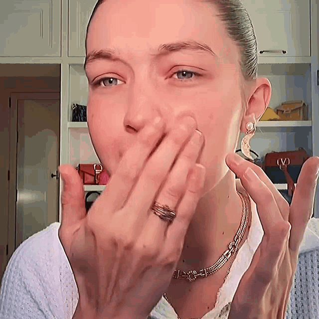 a woman covering her mouth with her hands while wearing a ring with the letter v on it