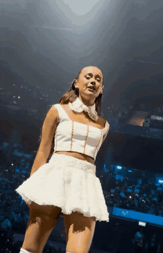 a woman in a white dress is standing on stage