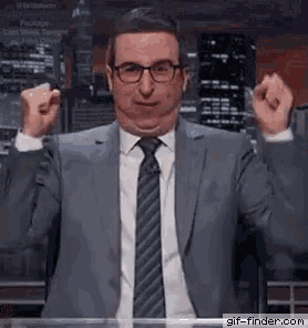 a man in a suit and tie is making a funny face while holding his fist in the air .